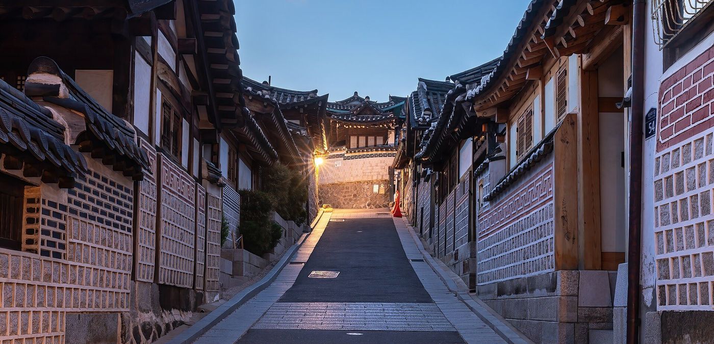 Hanok rooftops along a narrow Bukchon alley at blue hour, Seoul