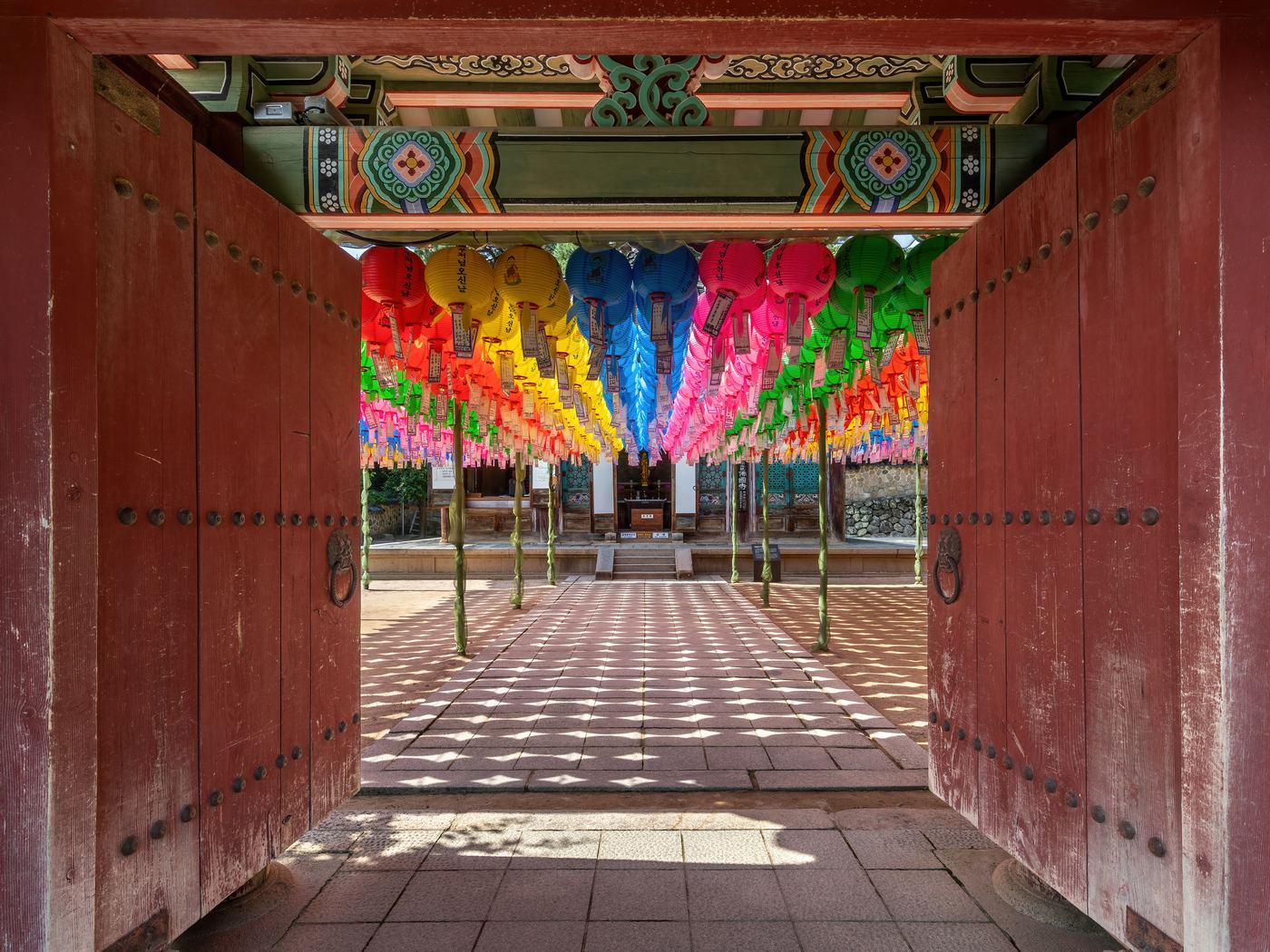An open gate looking through to a courtyard hung with coloured paper lanterns