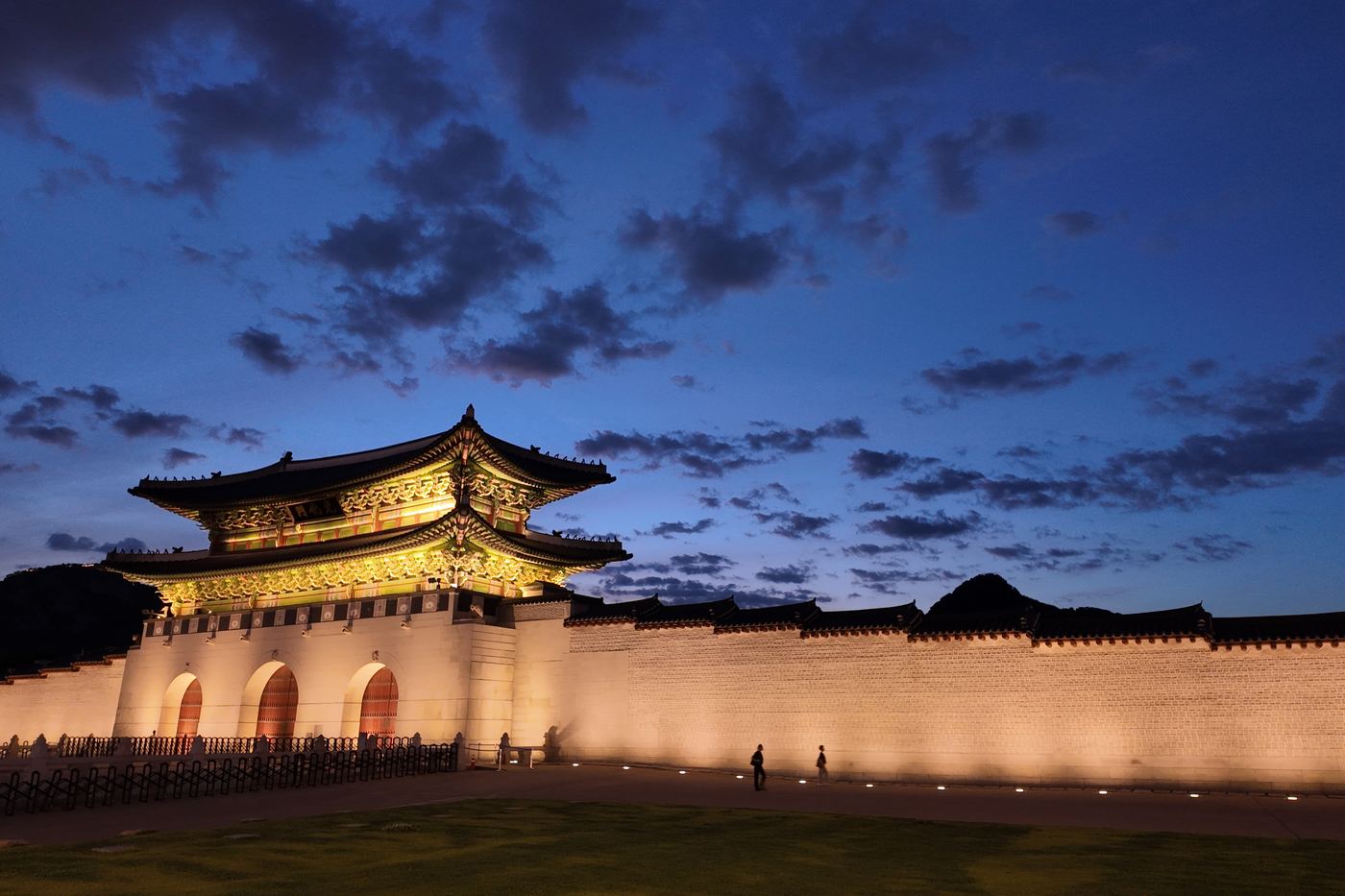 The lit wall and gate of Gyeongbokgung against a deep blue evening sky