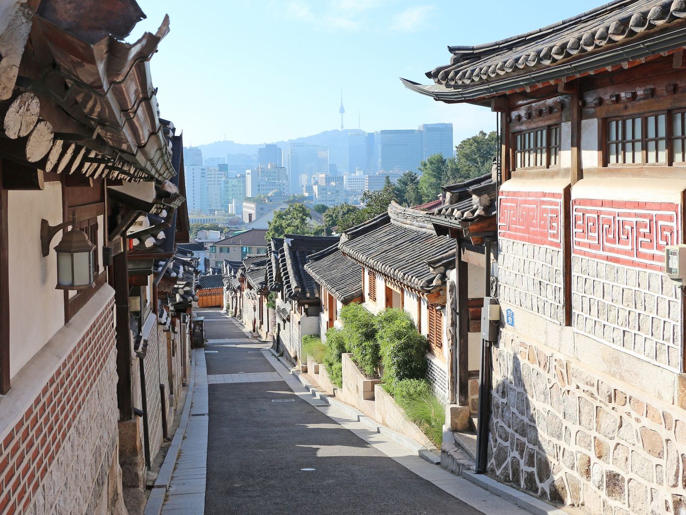 A hanok street in Bukchon, with the city and Namsan tower behind it
